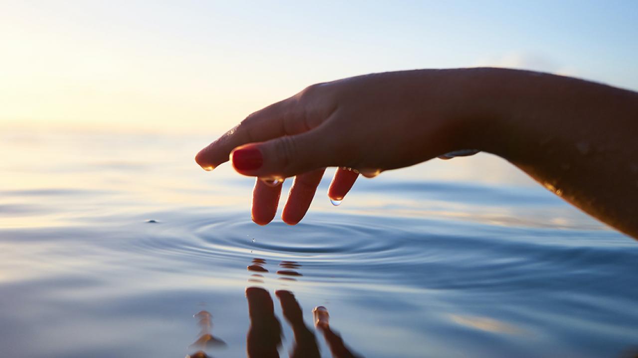 Image of a hand touching the surface of water